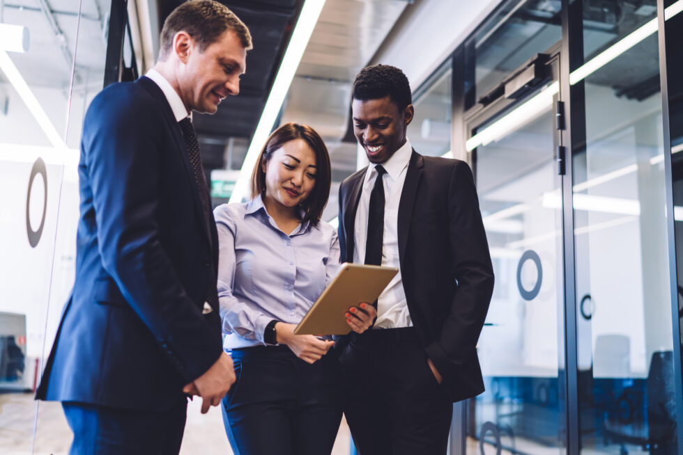 Three business professionals sharing a tablet to easily view AI-Enabled software